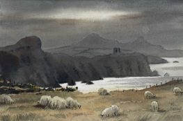 ‡ ALUN DAVIES watercolour - sheep grazing on headland above a bay with mountainous background,