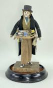 MALE PEDDLER DOLL, with kid leather body, dressed in top hat and coat selling coloured wallets and