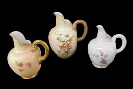 TWO ROYAL WORCESTER BLUSH IVORY FLAT BACK JUGS with reeded handles, the larger decorated with sprays