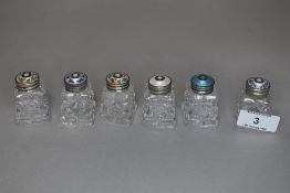 Six vintage cut glass bottles or jars having guilloche lids with floral details.