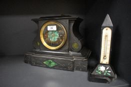An antique black marble mantel clock having green stone inset details and etched designs, brass
