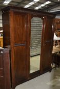 An early 20th Century mahogany triple wardrobe having mirror door, width approx. 158cm