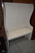 A painted settle of traditional form with upholstered cushion to seat