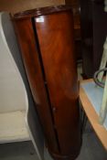 A reproduction drinks cabinet of cylindrical form with marble inset top