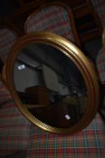 An oval hallway mirror with gilt effect frame