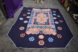 A large vintage patchwork quilt,around 1960s, floral and similar hexagons on navy blue ground.