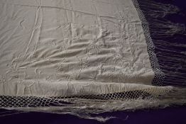 An antique cream silk shawl having extensive floral embroidery and deep fringing to edges.