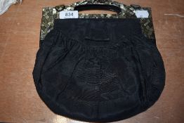 An early 20th century handbag having unusual shell like finish to framework handle, one clasp