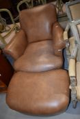A modern armchair and pouffe having tan leather upholstery and turned feet