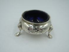A small Victorian silver salt cellar of cauldron form having trefoil hoof feet, moulded floral