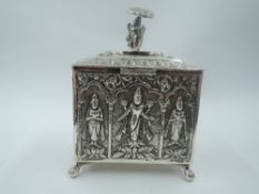 An Indian white metal canister having repousse Indian study panels and finial with ball and claw