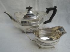 A matched silver tea pot and cream jug having gadrooned decoration to shaped flared rims, lion