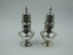 A pair of matched silver pepperettes of waisted urn form having push on pierced lids, London 1900/