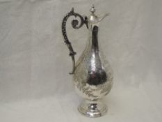A Victorian silver claret jug having hinged lid, moulded decorative scroll handle and engraved