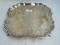 A silver salver having raised pie crust rim, hoof feet and presentation inscription to centre,