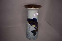 A porcelain vase being hand decorated with fish or carp imagery