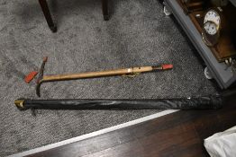 An antique wooden fishing rod and an ice axe military marked