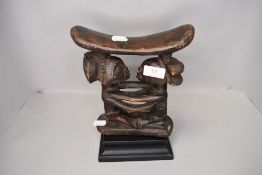 A genuine African tribal head rest carved from ethnic wood with two figures carved for supports