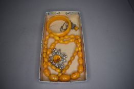 A small selection of amber style jewellery including bangle, beads, pendant and Celtic brooch