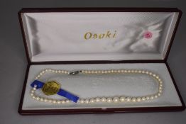 A cased string of graduated Osaki shell base pearls with white metal clasp, approx 18