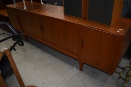 A mid century teak long side board having rolling doors and compartmental inside in good condition