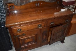 A late Victorian Art Nouveau reduced back sideboard having drawers and carved cupboards