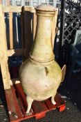 A metal cast three legged chiminea or fire pit