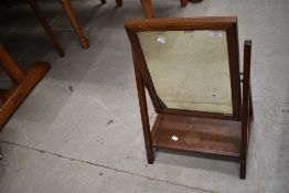 An Arts and Crafts golden oak toilet mirror having shelf base