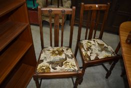 A set of four early 20th Century oak rail back dining chairs having scaramanga style decoration