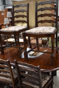 A Priory style dark oak dining table and set of four ladder back dining chairs