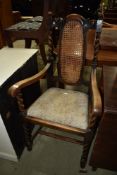 An early 20th Century oak carver chair having canework back panel and twist frame