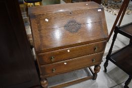 An early to mid 20th Century oak bureau having applique decoration to flap , two drawers and part
