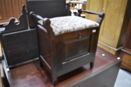 An early 20th Century mahogany stool with drop front compartment for music