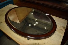 An early 20th Century mahogany framed oval wall mirror, hung in portrait orientation, approx 75 x