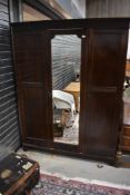 An early 20th Century mahogany triple wardrobe having mirror door, width approx. 158cm
