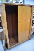 A vintage Austinsuite golden oak wardrobe having sliding doors, width approx 122cm
