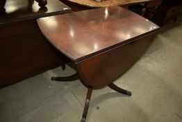 A reproduction Regency drop leaf dining table of small proportions having brass paw feet