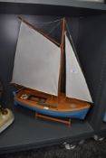 A model sailing yacht painted blue with stand