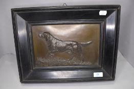 A late Victorian metal cast plaque of a hunting dog in ebonised frame