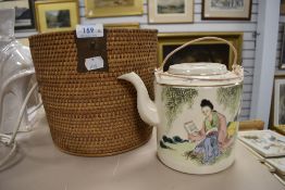 An unusual vintage hand painted oriental tea pot in padded basket.