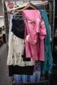 An assortment of colourful ladies dresses, predominantly 1970s, mixed sizes and styles.
