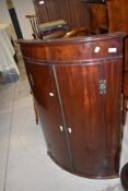 A Victorian bow fronted corner cupboard in mahogany
