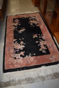 A Chinese style fireside rug, black and peach ground