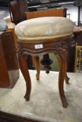 A Victorian piano stool having carved floral cabriole legs with adjustable top