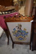 An Edwardian mahogany framed fire screed having embroidered armorial motiff