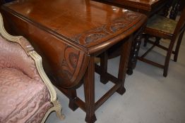 An early 20th Century gateleg dining table having carved edge