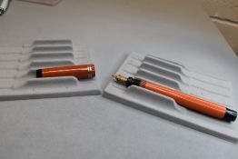 A Parker Duofold Lucky Curve button fill fountain pen in orange with two narrow bands to the cap