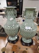 Two carved natural stone vases having wooden stands.