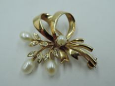 A 9ct gold brooch in the form of a tied sprig having baroque pearl and diamond chip decoration,