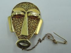 A yellow metal brooch in the form of a tribal mask, possibly Ethiopian, no marks, tests as 22ct